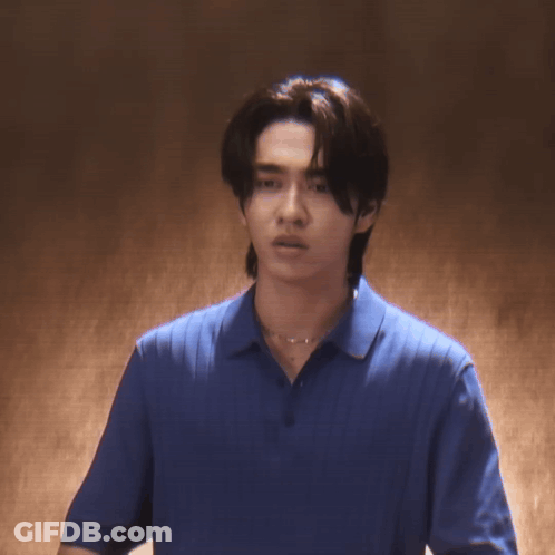 A Young Man Wearing A Blue Shirt And A Necklace Is Looking At The Camera GIF