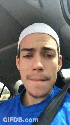 A Young Man Wearing A Blue Shirt And A White Headband Looks At The Camera GIF