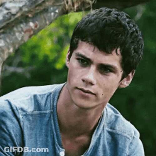 A Young Man Wearing A Blue Shirt Is Sitting Under A Tree . GIF