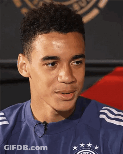 A Young Man Wearing A Blue Shirt With Stars On It Looks To The Side GIF