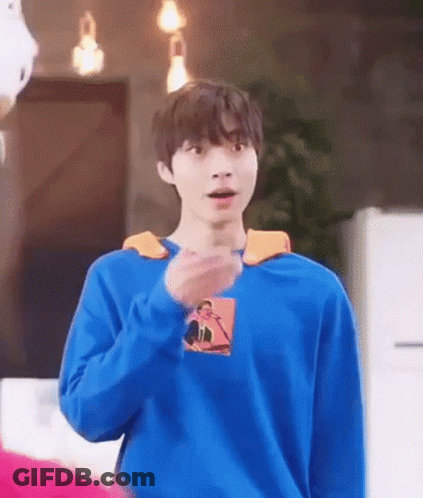 A Young Man Wearing A Blue Sweater Is Standing In A Room . GIF