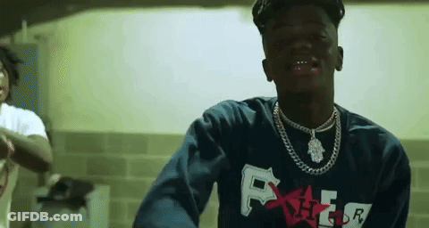A Young Man Wearing A Blue Sweatshirt And A Necklace Is Standing In A Room . GIF