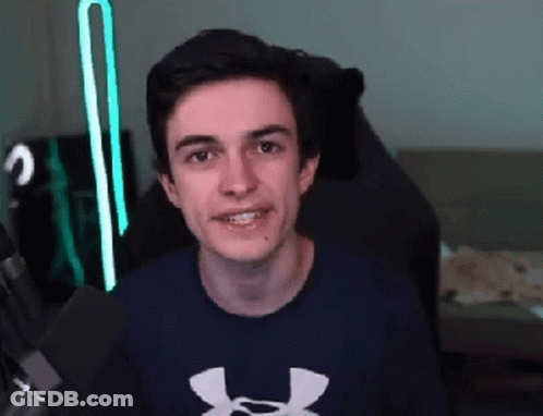 A Young Man Wearing A Blue Under Armour Shirt Is Sitting In A Chair And Smiling . GIF