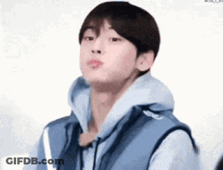 A Young Man Wearing A Blue Vest And A Hoodie Is Making A Face . GIF