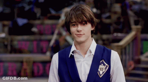 A Young Man Wearing A Blue Vest With A Badge That Says 25 On It GIF