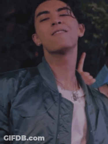 A Young Man Wearing A Bomber Jacket And A White Shirt Is Giving A Thumbs Up GIF