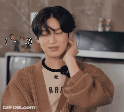 A Young Man Wearing A Brown Cardigan And A White Shirt With The Word Rri On It GIF