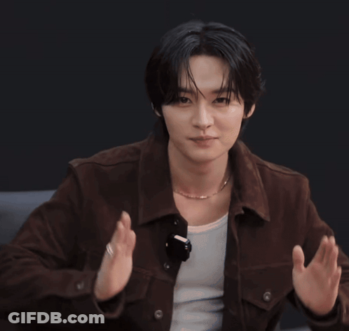 A Young Man Wearing A Brown Jacket And A Necklace Is Clapping GIF