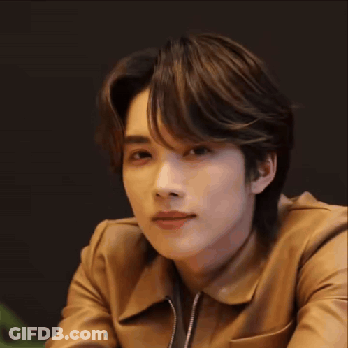 A Young Man Wearing A Brown Leather Jacket Is Smiling . GIF