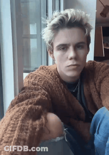 A Young Man Wearing A Brown Sweater Takes A Selfie GIF
