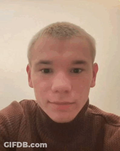 A Young Man Wearing A Brown Turtleneck Sweater Is Taking A Selfie GIF