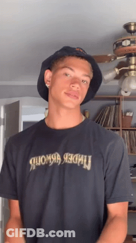 A Young Man Wearing A Bucket Hat And A T-Shirt That Says Under Armour GIF