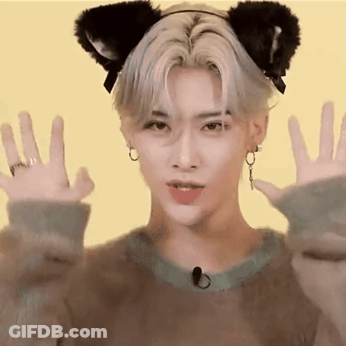 A Young Man Wearing A Cat Ear Headband Is Making A Cat Face With His Hands . GIF
