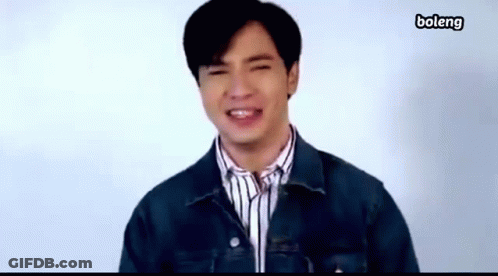 A Young Man Wearing A Denim Jacket And Striped Shirt Is Smiling . GIF