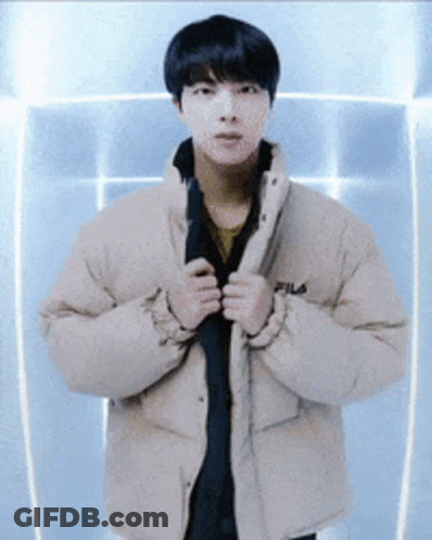 A Young Man Wearing A Fila Jacket Is Standing In Front Of A Blue Wall GIF