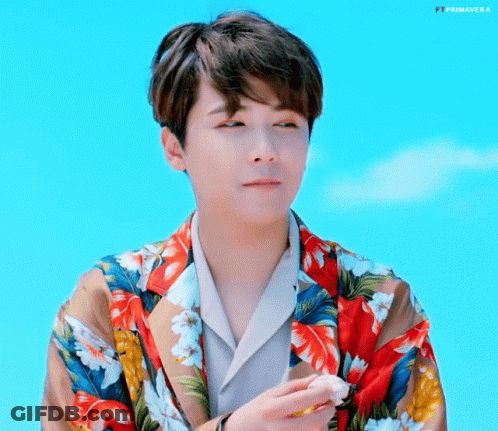 A Young Man Wearing A Floral Shirt Is Holding A Piece Of Food . GIF