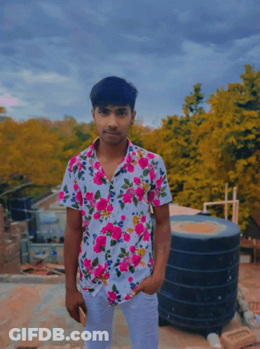 A Young Man Wearing A Floral Shirt Is Standing On A Roof GIF