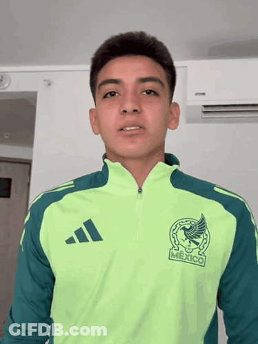 A Young Man Wearing A Green Adidas Jacket With Mexico On The Front GIF