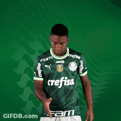 A Young Man Wearing A Green Crefisa Jersey Holds Out His Hand GIF
