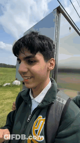 A Young Man Wearing A Green Jacket With The Letter T On It GIF