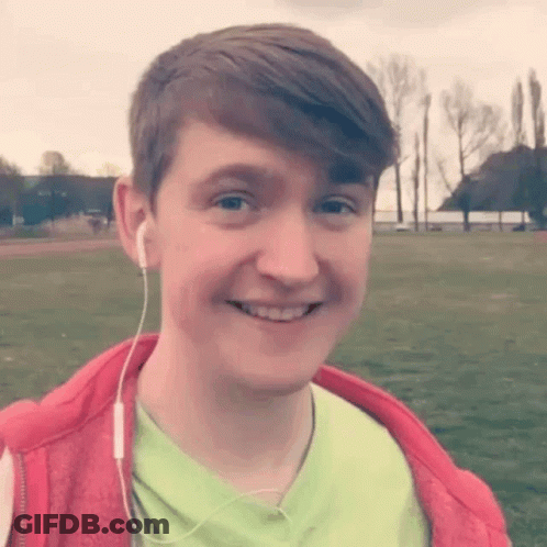 A Young Man Wearing A Green Shirt And A Red Jacket Is Smiling . GIF