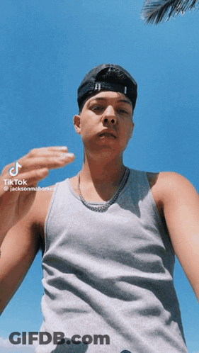 A Young Man Wearing A Hat And A Tank Top Is Taking A Selfie With Tik Tok GIF