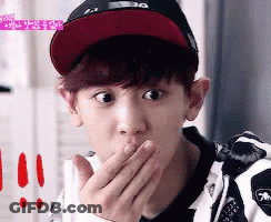 A Young Man Wearing A Hat Is Covering His Mouth With His Hands GIF