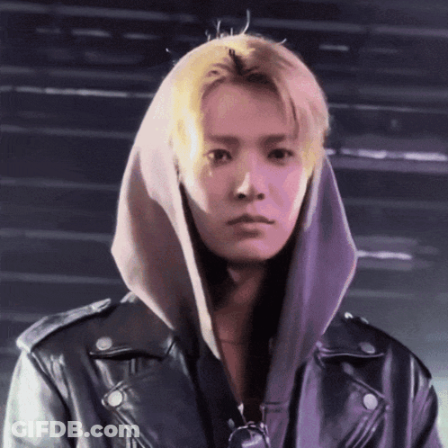 A Young Man Wearing A Hoodie And A Leather Jacket Looks At The Camera GIF