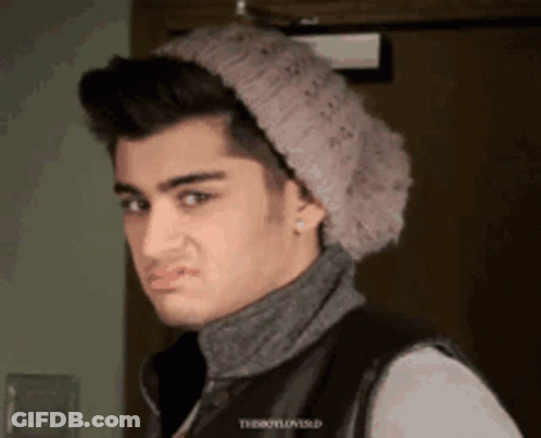 A Young Man Wearing A Knitted Hat And A Turtleneck Is Making A Face GIF