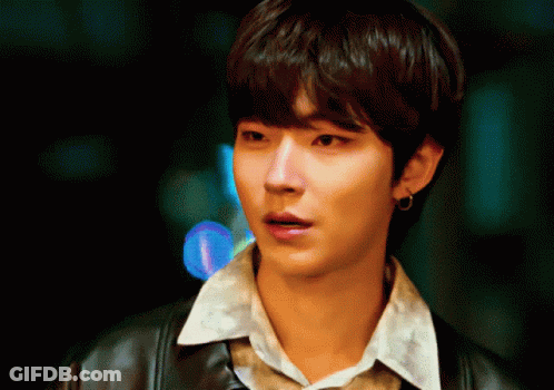 A Young Man Wearing A Leather Jacket And A White Shirt Looks At The Camera GIF