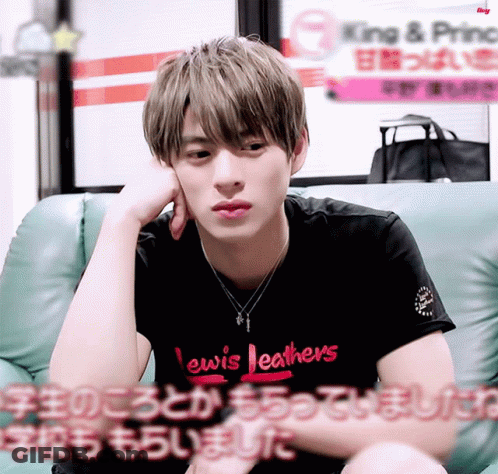 A Young Man Wearing A Lewis Leathers Shirt Sits On A Green Couch GIF