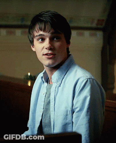 A Young Man Wearing A Light Blue Shirt And A Grey Sweater GIF
