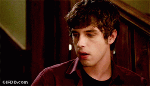 A Young Man Wearing A Maroon Shirt And A Black Shirt Is Making A Funny Face GIF