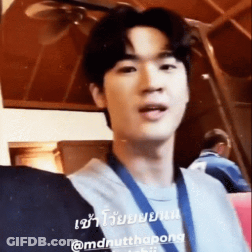 A Young Man Wearing A Medal Around His Neck Is Standing In A Room With Other People . GIF