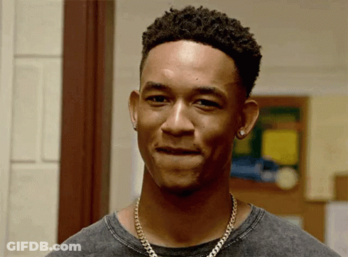A Young Man Wearing A Necklace And Earrings Is Smiling . GIF