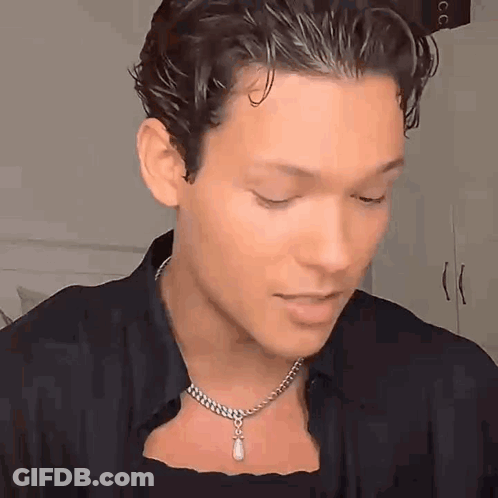 A Young Man Wearing A Necklace With A Pearl Pendant On His Neck . GIF