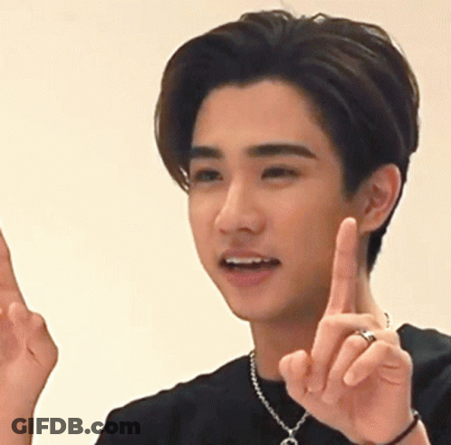 A Young Man Wearing A Necklace With The Letter C On It Is Pointing Up GIF
