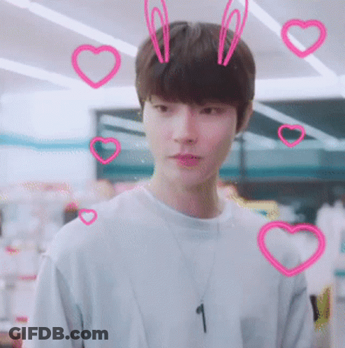 A Young Man Wearing A Necklace With The Number 1 On It Surrounded By Pink Hearts GIF