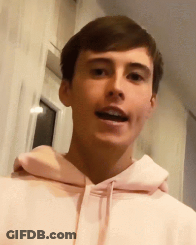 A Young Man Wearing A Pink Hoodie Is Making A Funny Face GIF