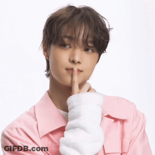 A Young Man Wearing A Pink Jacket Is Holding His Finger To His Mouth . GIF
