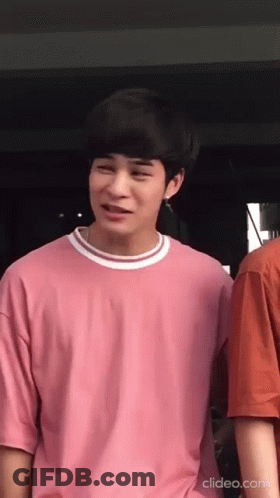 A Young Man Wearing A Pink T-Shirt Is Standing Next To Another Young Man . GIF