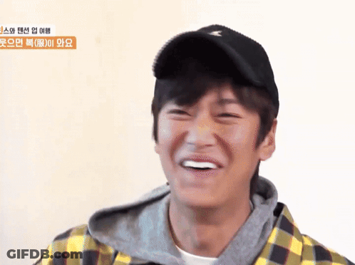 A Young Man Wearing A Plaid Shirt And A Black Hat Smiles GIF