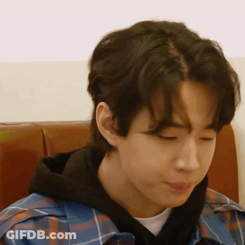 A Young Man Wearing A Plaid Shirt And A Black Hoodie Is Sitting In A Chair . GIF