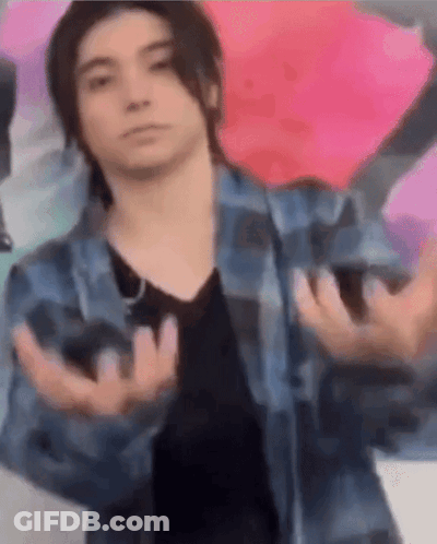 A Young Man Wearing A Plaid Shirt And A Black Shirt Is Making A Funny Face With His Hands Outstretched . GIF