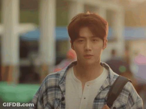 A Young Man Wearing A Plaid Shirt And Carrying A Backpack Looks At The Camera GIF