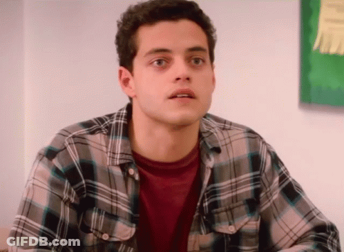 A Young Man Wearing A Plaid Shirt Looks Surprised GIF