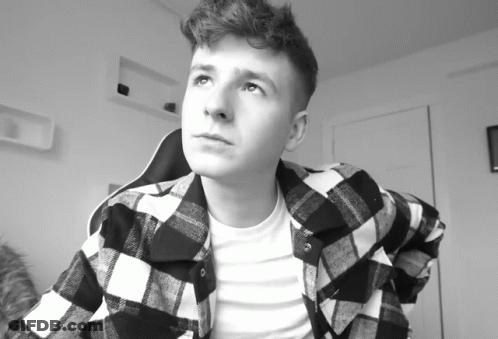 A Young Man Wearing A Plaid Shirt Looks Up GIF