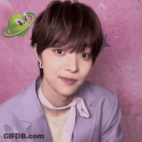 A Young Man Wearing A Purple Jacket And A White Scarf Looks At The Camera In Front Of A Pink Background GIF