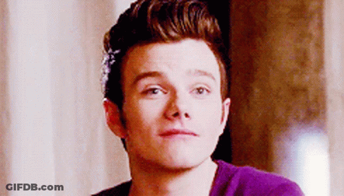 A Young Man Wearing A Purple Shirt Is Looking At The Camera . GIF