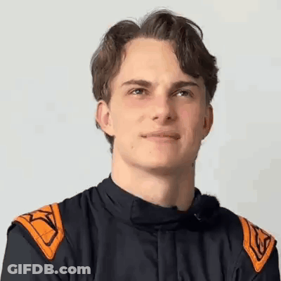 A Young Man Wearing A Racing Suit Is Smiling For The Camera . GIF